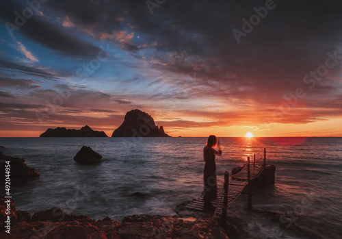 Red sunset in Cala d,Hort with girl on bridge with  Es Vedra Island  , Ibiza .