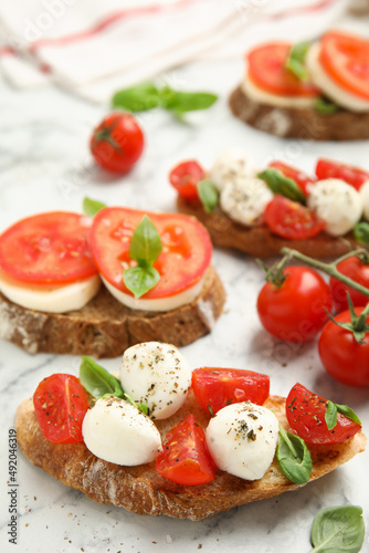 Delicious sandwiches with mozzarella, fresh tomatoes and basil on white marble table