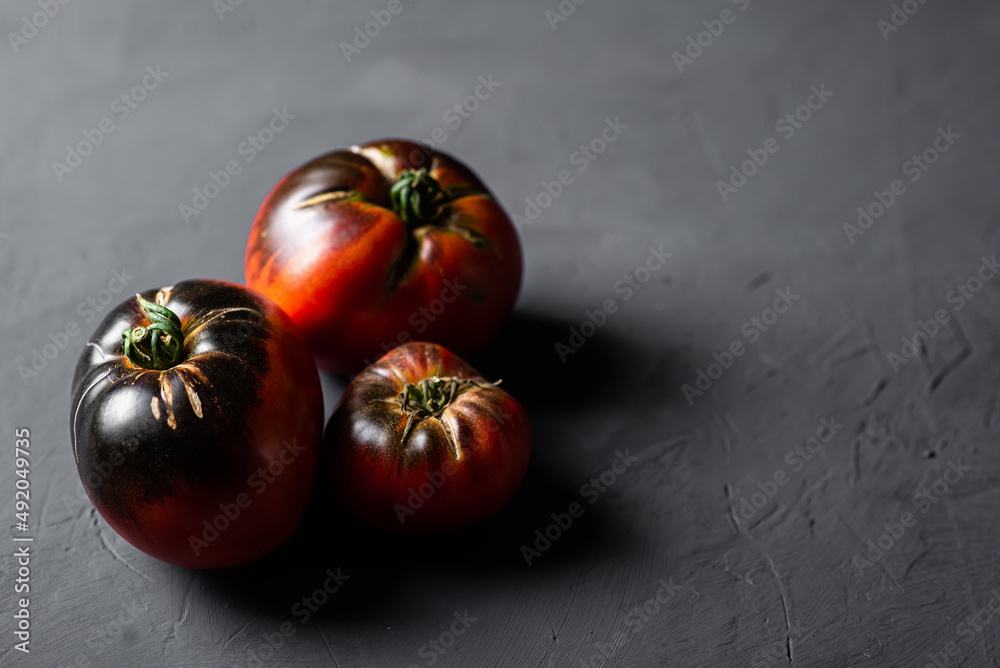 Red-black tomatoes of the bovine heart variety on a black background. Red-black tomatoes of the bovine heart variety on a black background.