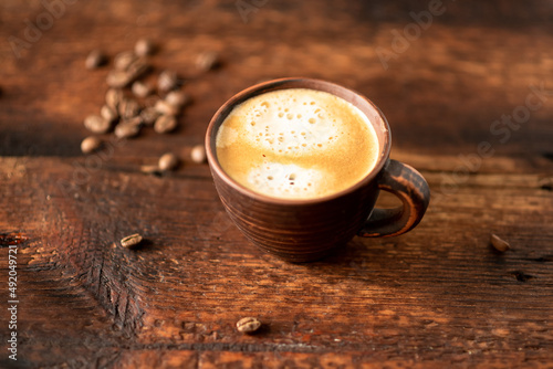 Cup with coffee and coffee beans on a wooden background.