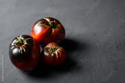 Red-black tomatoes of the bovine heart variety on a black background.
