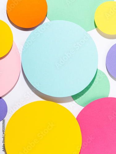Fun bright coloured mosaic of paper circles in pink, blue, yellow and purple colours. Minimalist background in pastel tones. Creative conceptual template for styling and design. Mock up for text.