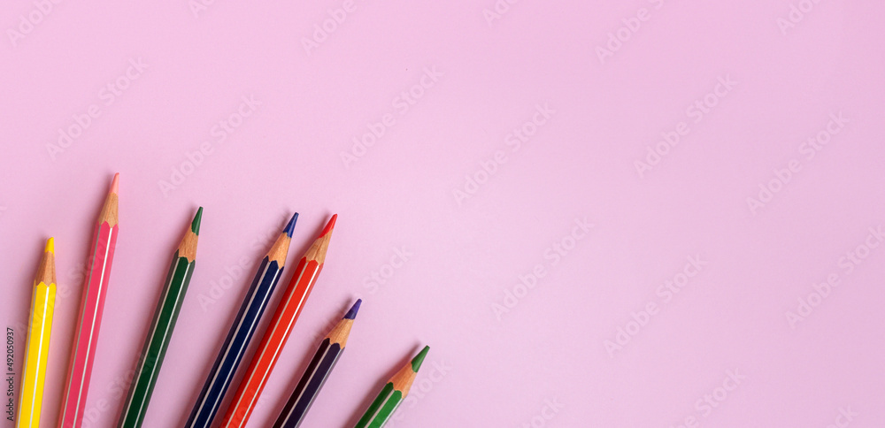 Color pencils on a light pink background. Top view with space for text. Back to school concept. Flat lay stationery mockup. Bright backplate for your design. Spectrum of different colors Color pencils on a light pink background. Top view with space for text. Back to school concept. Flat lay stationery mockup. Bright backplate for your design. Spectrum of different colors