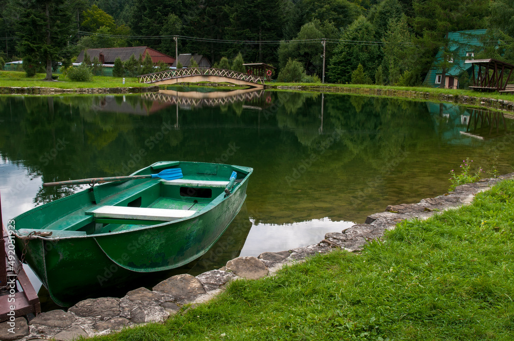 Boat on the shores of a mountain lake, calm water and green forest Boat on the shores of a mountain lake, calm water and green forest