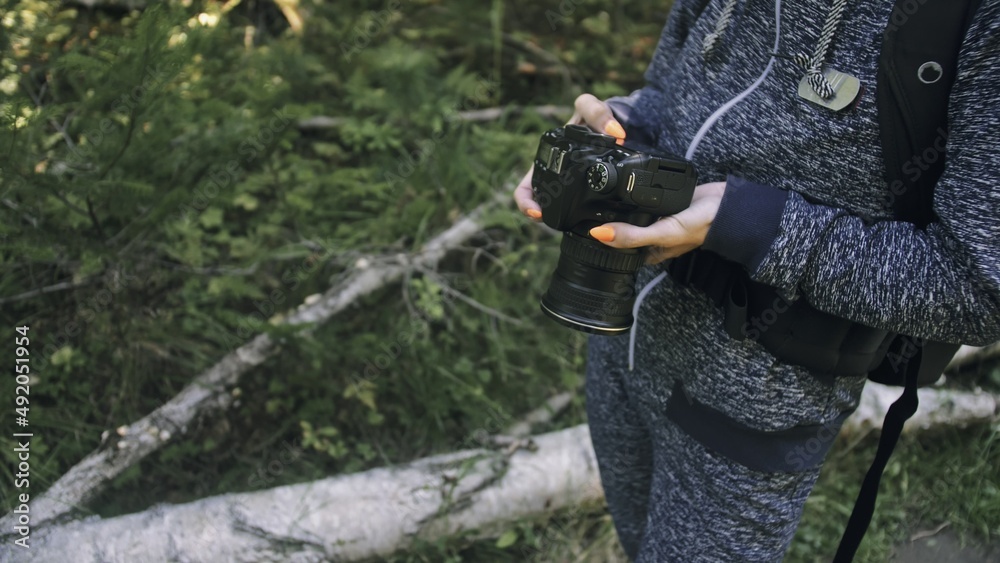 Naklejka premium Traveler photographing scenic view in forest. One caucasian woman shooting close up look. Girl take photo video on dslr mirrorless camera. Professional photographer travel with backpack. Outdoor.