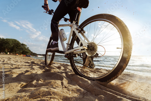 man on a bicycle slowly moving along a sandy beach. photo
