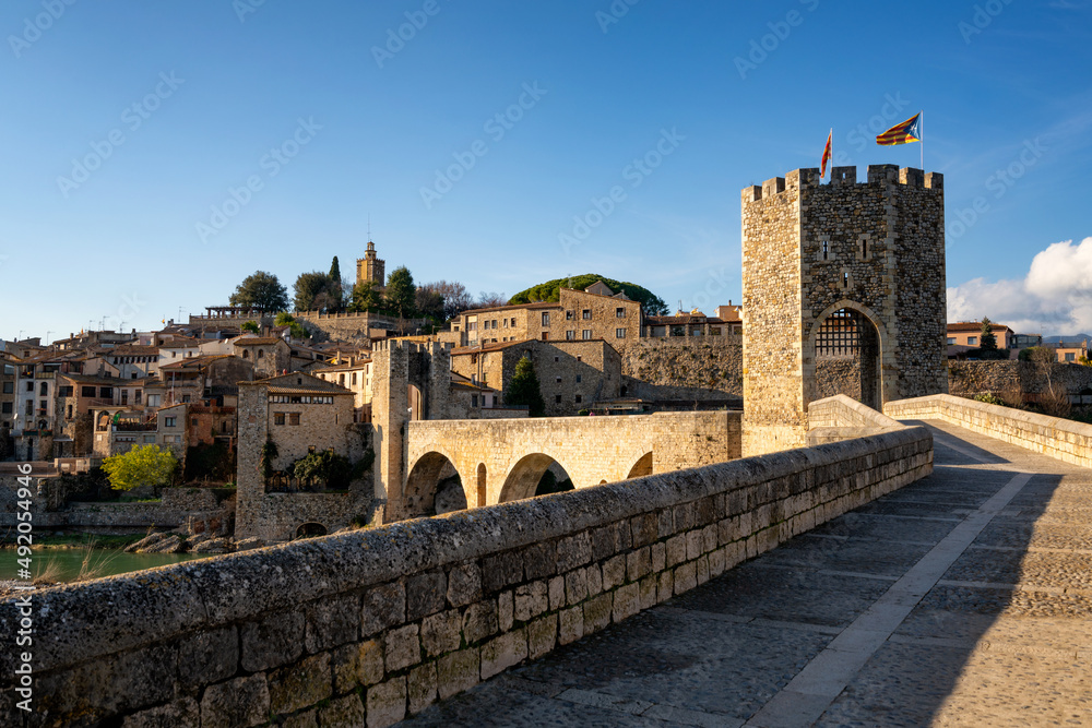 Besalu historic medieval city with Catalonia flags on the stone bridge tower crossing El Fluvia river, in Spain
