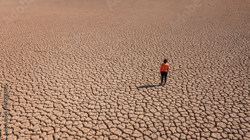 Fotografia Silhouette of a man on a sandy cracked empty not fertile land during a drought