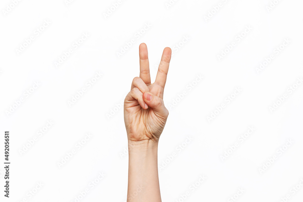 A female hand showing a peace gesture isolated on a white background. Victory hand sign A female hand showing a peace gesture isolated on a white background. Victory hand sign