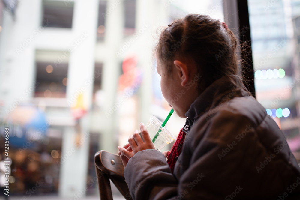 窓の外を眺めながらジュースを飲む女の子 窓の外を眺めながらジュースを飲む女の子