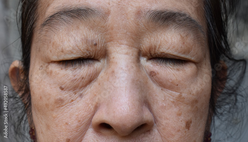 Face of Asian elder woman with closed eyes. Concept of aging. photo