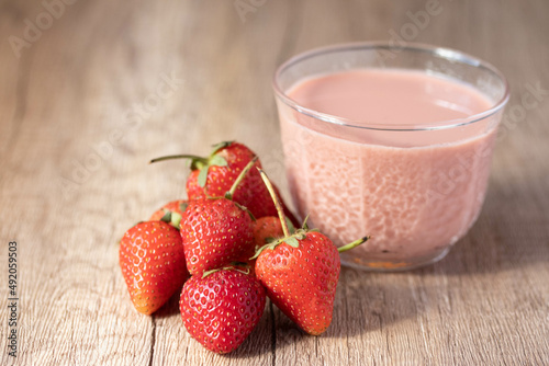 Strawberry flavored milk in clear glass on wooden background