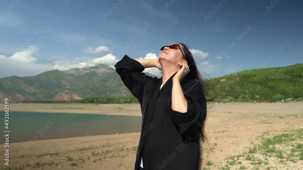 a girl in a black dress is standing on the shore of the lake a girl in a black dress is standing on the shore of the lake