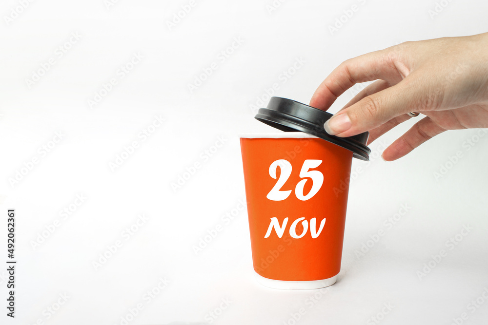 November 25th. Day 25 of month, Calendar date. A woman's hand open black plastic cap of red disposable cardboard coffee paper cup with Calendar Date. Autumn month, day of the year concept.