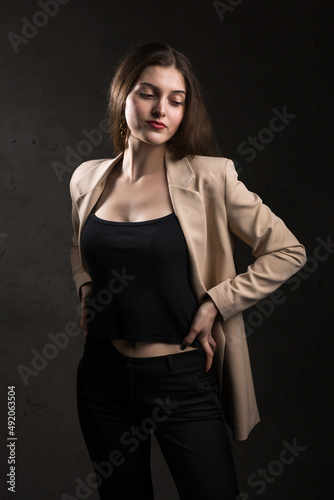 Portrait of a young brunette with long hair in the studio. Dramatic photo in dark colors.