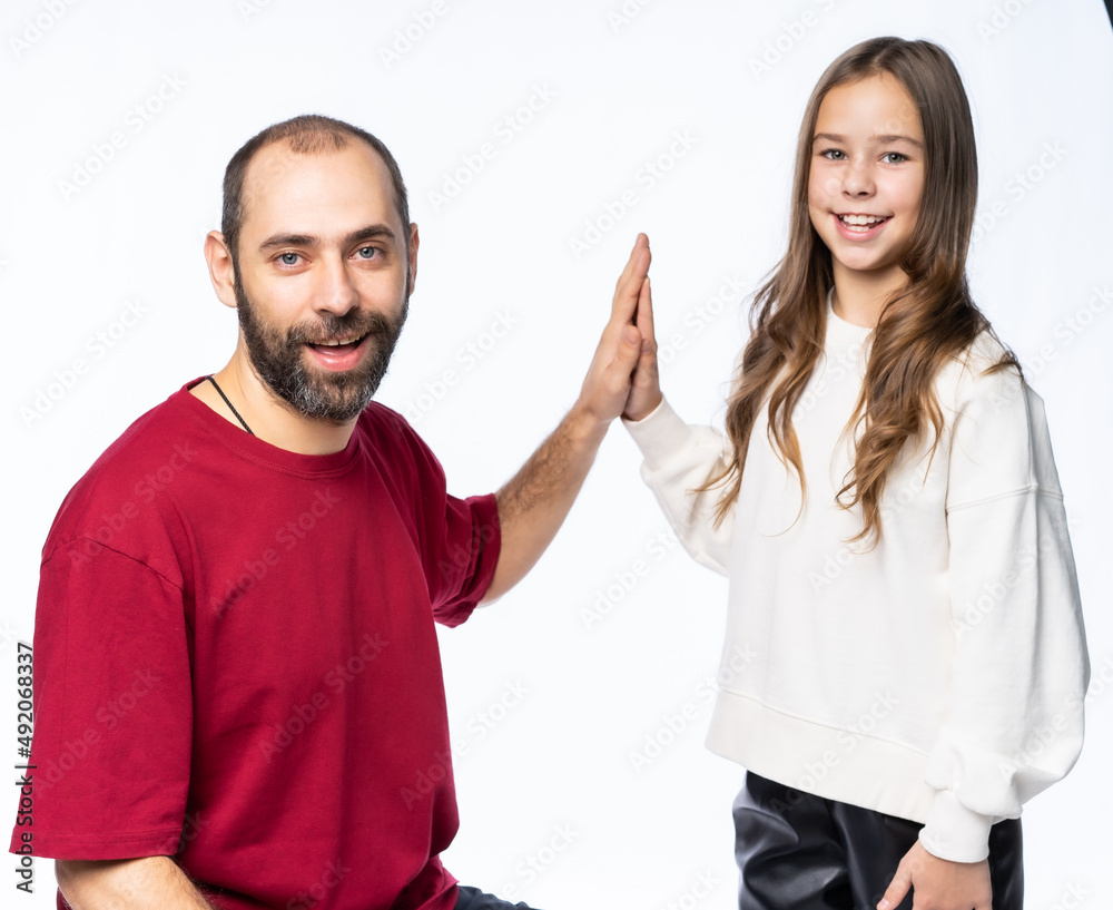 dad claps daughter on the palm in the studio. gives pap. a man in a burgundy-red T-shirt, a girl in a white sweatshirt. isolated white background dad claps daughter on the palm in the studio. gives pap. a man in a burgundy-red T-shirt, a girl in a white sweatshirt. isolated white background