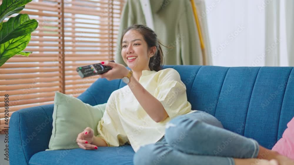 attractive young asian woman in casual sitting on sofa and happy feeling with remote control in hands while watching TV.Domestic lifestyles and people concept.lifestyle holiday at home concept. attractive young asian woman in casual sitting on sofa and happy feeling with remote control in hands while watching TV.Domestic lifestyles and people concept.lifestyle holiday at home concept.