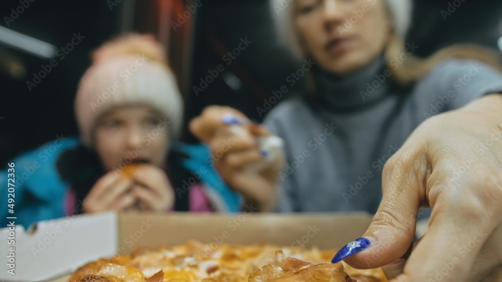 Mother and daughter eat pizza cheese four. Close up of young woman eating pizza and chewing in outdoor restaurant. Girl hands taking pieces slices of hot tasty italian pizza from open box.