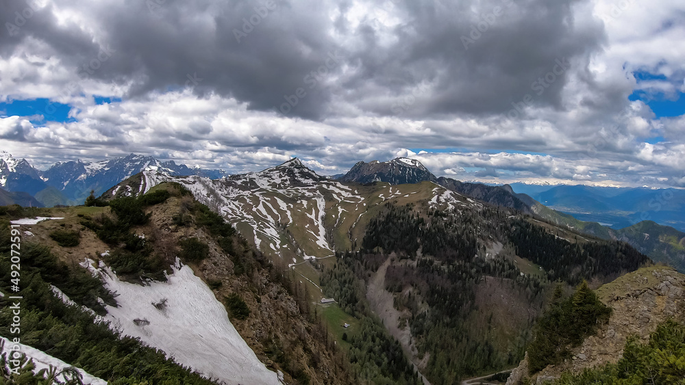 Mountain peak of Hahnkogel (Klek) with panoramic view in spring in the Karawanks, Carinthia, Austria. Borders Austria, Slovenia, Italy. Triglav National Park. Alpine meadows. Alm. Snow fields melting Mountain peak of Hahnkogel (Klek) with panoramic view in spring in the Karawanks, Carinthia, Austria. Borders Austria, Slovenia, Italy. Triglav National Park. Alpine meadows. Alm. Snow fields melting
