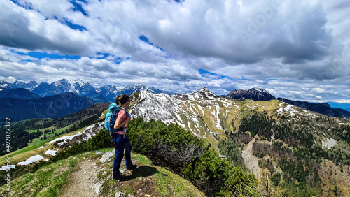 Hiker woman with backpack at summit of Hahnkogel (Klek) with scenic view on mountain peaks in Karawanks and Julian Alps, Carinthia, Austria. Border with Slovenia. Triglav National Park. Goal seeking
