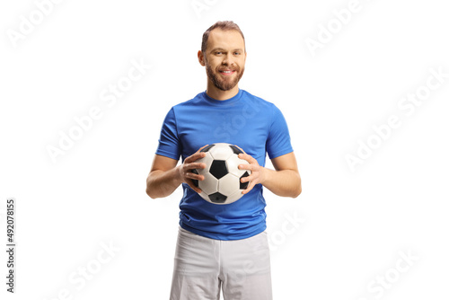 Football player in a blue jersey and white shorts holding a ball and smiling