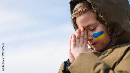 Tableau sur toile Ukrainian boy closed her eyes and praying to stop the war in Ukraine
