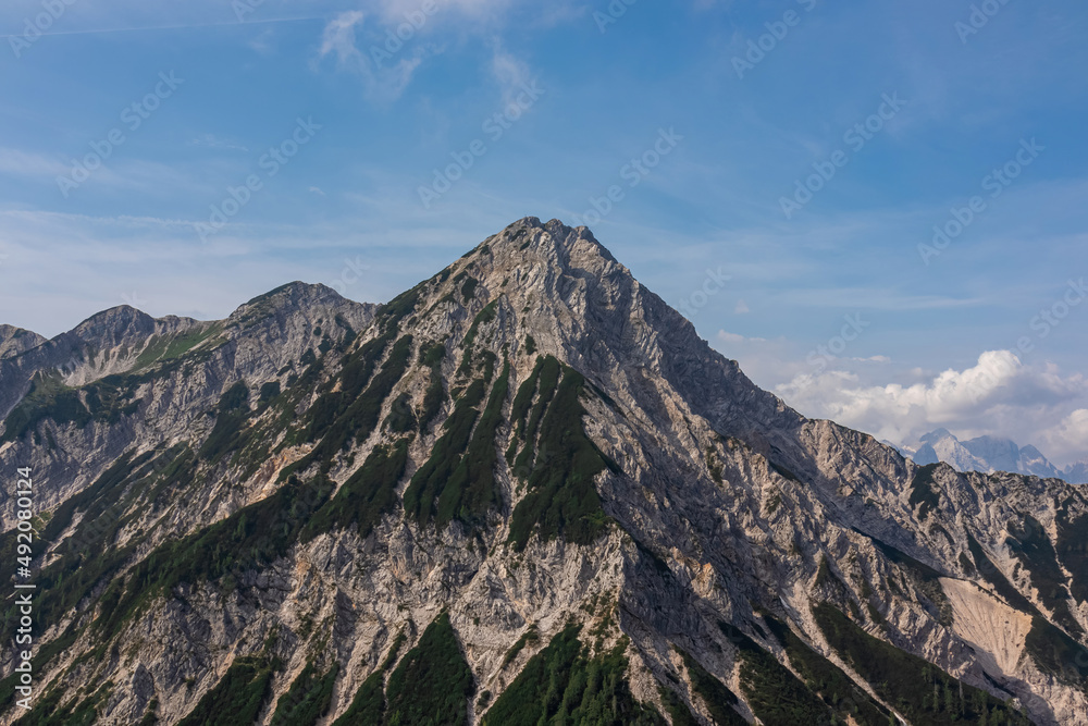 Scenic view from Ferlacher Spitze on summit mount Mittagskogel in the Karawanks in Carinthia, Austria. Borders between Austria, Slovenia, Italy. In back Julian Alps and the Triglav National Park. Scenic view from Ferlacher Spitze on summit mount Mittagskogel in the Karawanks in Carinthia, Austria. Borders between Austria, Slovenia, Italy. In back Julian Alps and the Triglav National Park.