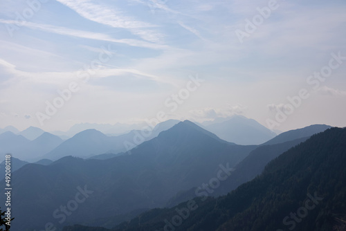 Scenic view on the alpine mountain chains of the Karawanks in Carinthia  Austria. Peaks are shrouded in morning fog. Mystical vibes. Clear and sunny day. Serenity. View from Ferlacher Spitze  Alps