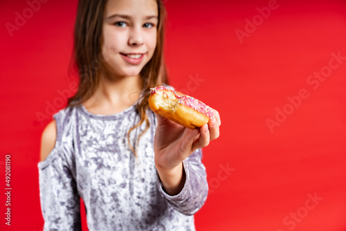 portrait of a beautiful girl in a gray dress with loose hair. teenager with donut. on a red background