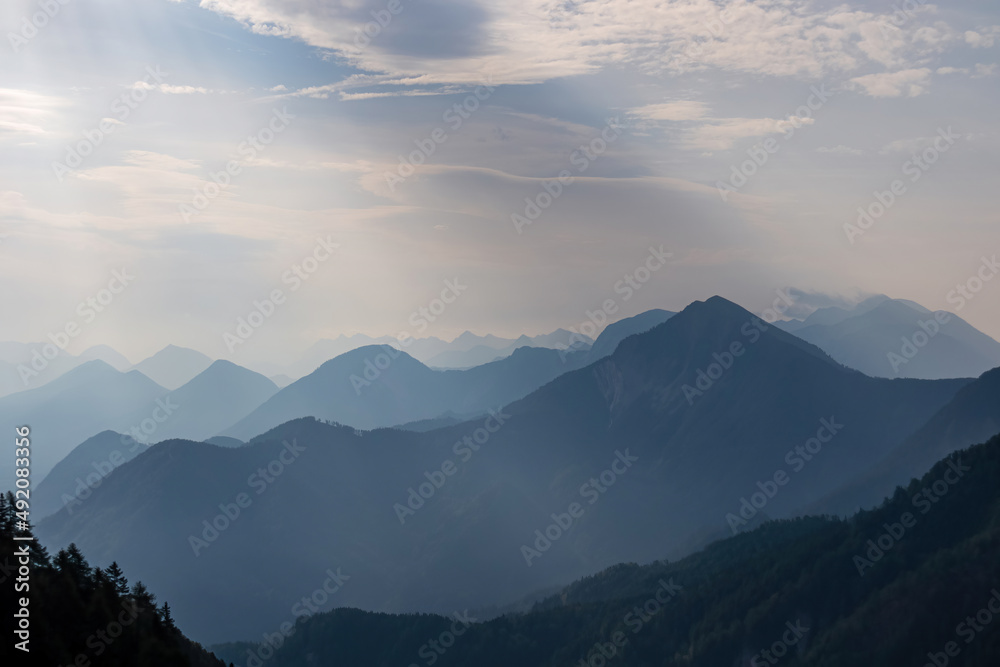 Scenic view on the alpine mountain chains of the Karawanks in Carinthia, Austria. Peaks are shrouded in morning fog. Mystical vibes. Clear and sunny day. Serenity. View from Ferlacher Spitze, Alps