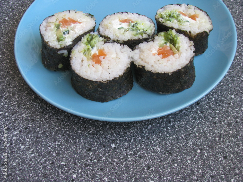Homemade sushi in a blue plate. Rolls in a plate on the table.