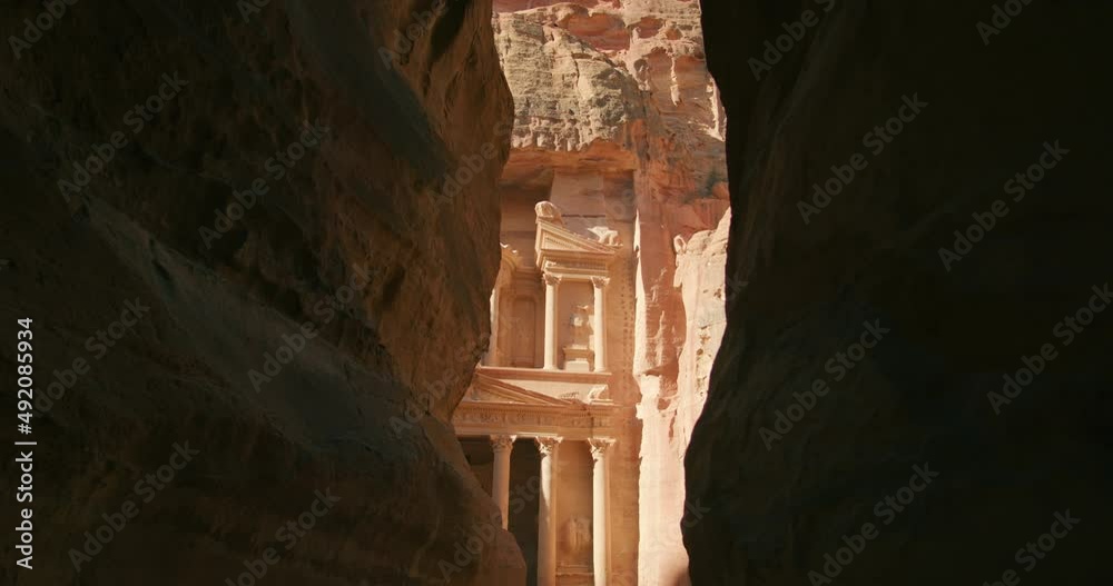 The Siq gorge opens to Petra's temple - Treasury Al-Khazneh. Temples carved out of sandstone rock face in Nabatean city inhabited by Arabs in ancient times. Most popular tourist attraction in Jordan.
