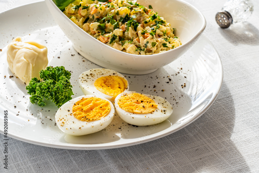 Vegetable mayonnaise salad with hard boiled eggs on white table
Vegetable mayonnaise salad with hard boiled eggs on white table