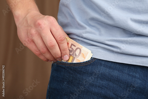 Man putting money into pocket of jeans, closeup