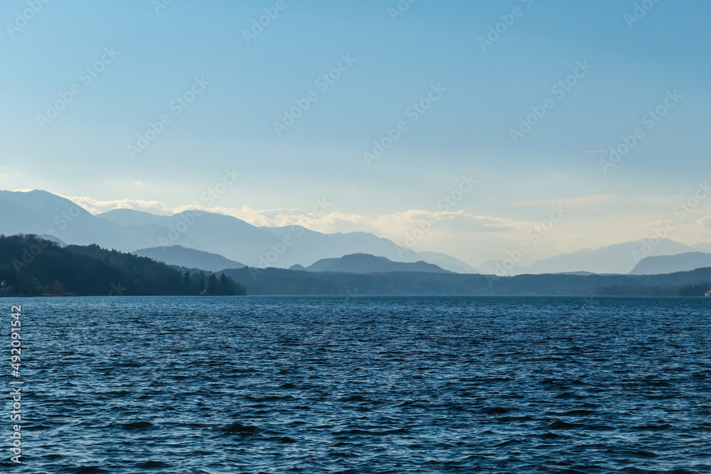 Scenic view on Woerthersee in Poertschach in Carinthia, Austria. View on the Karawanks , Austrian Alps. The water surface is wavy. Sunny day with clear sky. Relaxed feeling. Lake Woerth
