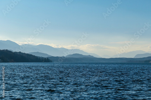 Scenic view on Woerthersee in Poertschach in Carinthia  Austria. View on the Karawanks   Austrian Alps. The water surface is wavy. Sunny day with clear sky. Relaxed feeling. Lake Woerth