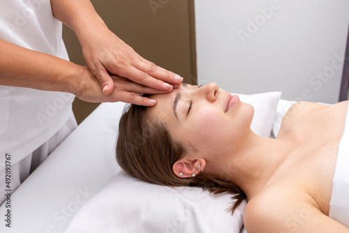 young woman in an aesthetic and spa center performing a beauty treatment for body and skin care with a reiki technique with feathers and stones and body massages