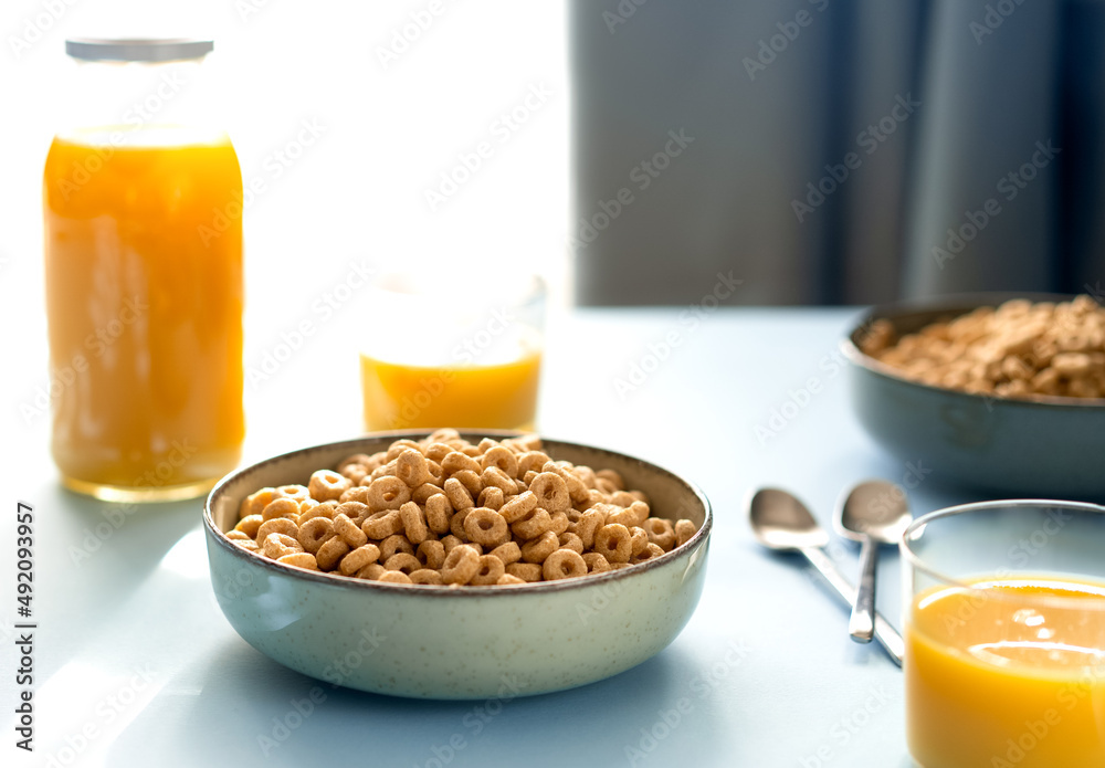 Breakfast concept with cold cereals and orange juice on blue background Breakfast concept with cold cereals and orange juice on blue background