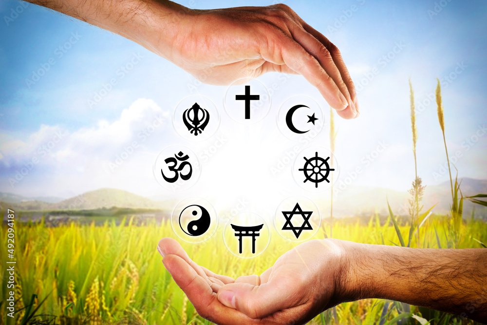Hands encompassing symbols of various religions with nature background ...