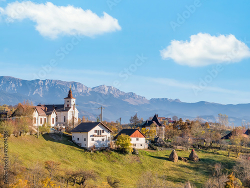 Beautiful rustic landscape in Magura village,Romania, with traditional romanian houses, a church and Piatra Craiului mountains in the background