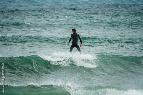 Young man in a black wetsuit surfing a wave with his board on the island of Lanzarote in the Canary Islands