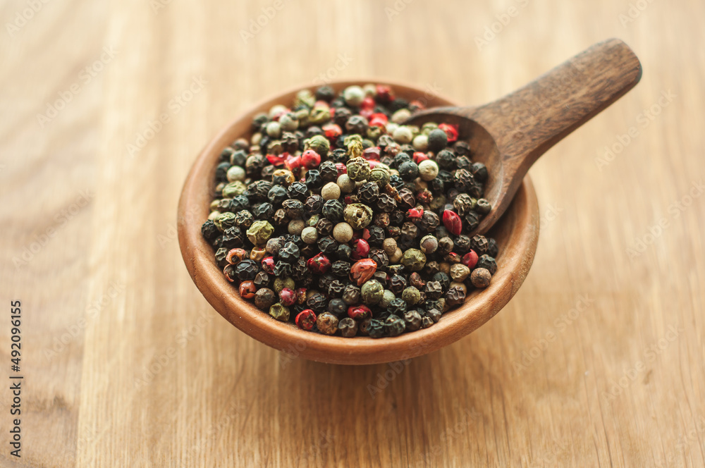 peppercorns, black pepper, white, green, red pepper, aromatic seasoning, spices, cooking ingredients, top view, in a wooden bowl on a wooden background, space for text peppercorns, black pepper, white, green, red pepper, aromatic seasoning, spices, cooking ingredients, top view, in a wooden bowl on a wooden background, space for text