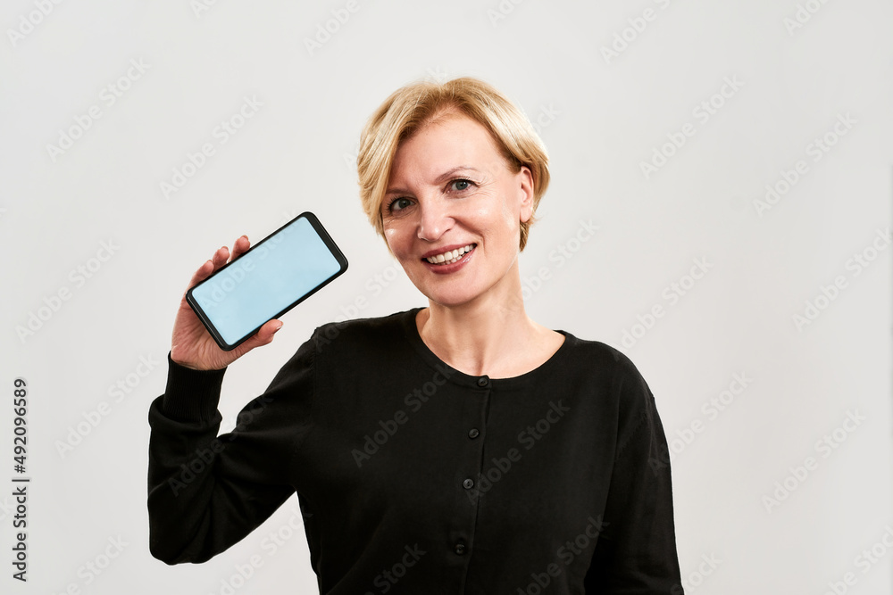 Fototapeta premium Front view of smiling woman showing mobile phone