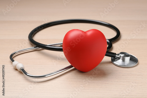 Stethoscope and red decorative heart on wooden background. Cardiology concept