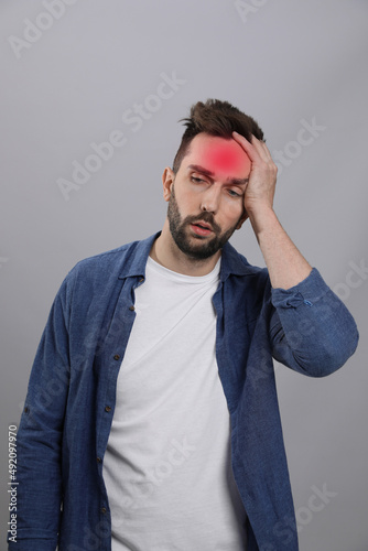 Man suffering from headache on grey background. Cold symptoms