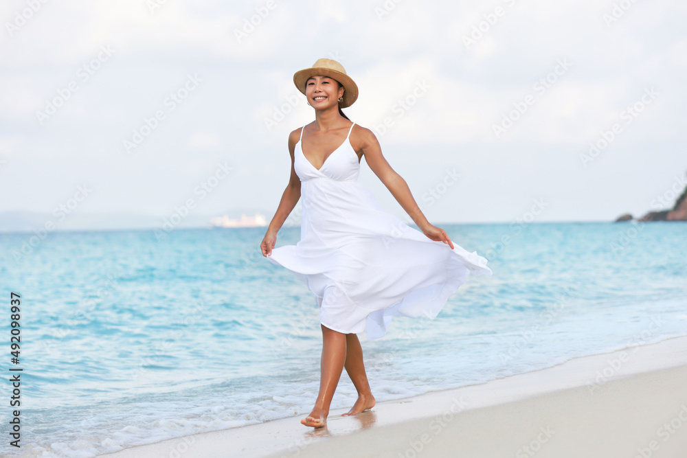 Beautiful tanned woman with white long dress walk relaxation on beach, summver vacation concept Beautiful tanned woman with white long dress walk relaxation on beach, summver vacation concept