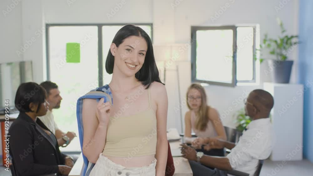 Confident young businesswoman in a meeting. Happy successful girl posing with brainstorming multiethnic colleagues. Holding a coat. Confident young businesswoman in a meeting. Happy successful girl posing with brainstorming multiethnic colleagues. Holding a coat.