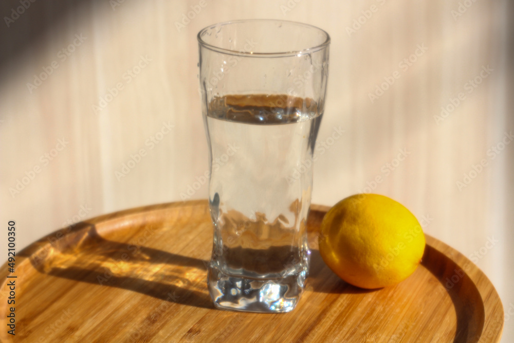 A glass of water and lemon in the morning light. Diet, weight control. A glass of water and lemon in the morning light. Diet, weight control.