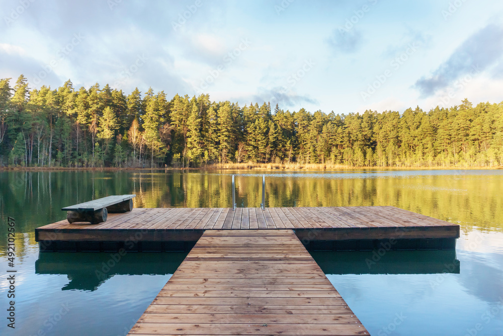 Obraz premium Pier with a bench on a beautiful lake in autumn