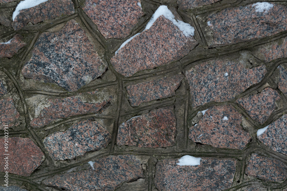 Fototapeta premium Background texture of the fortification wall, of textured wild stone. Part of the wall of an ancient fortress built of wild stone.